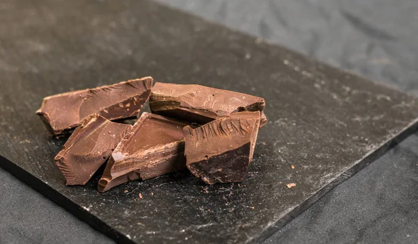 Chocolate with chocolate chips against black background. — Stock Photo, Image