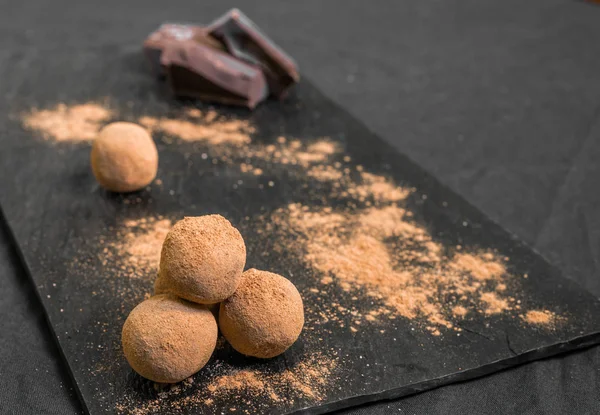 Chocolate truffle candy coated in cocoa powder against black background. — Stock Photo, Image
