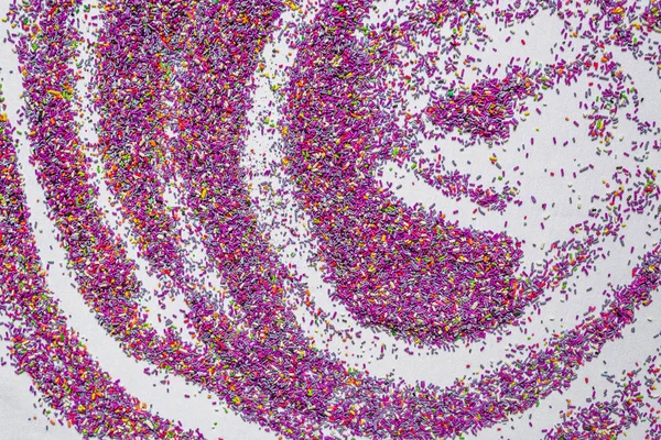 Background of colorful purple sprinkles. Food texture and pattern.