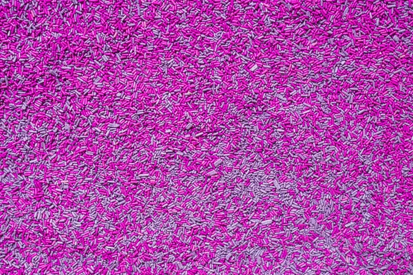 Background of colorful purple sprinkles. Food texture and pattern.