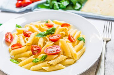 Kiraz domates ve fesleğen yaprakları ile renkli penne rigate makarna çanak.