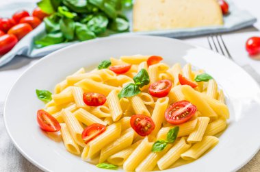 Kiraz domates ve fesleğen yaprakları ile renkli penne rigate makarna çanak.