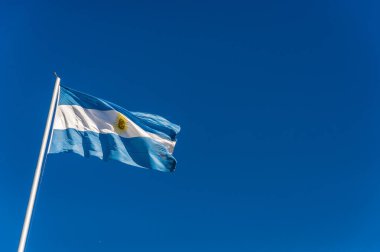 Arjantin bayrağı güneşli bir günde mavi gökyüzüne karşı el sallıyor.