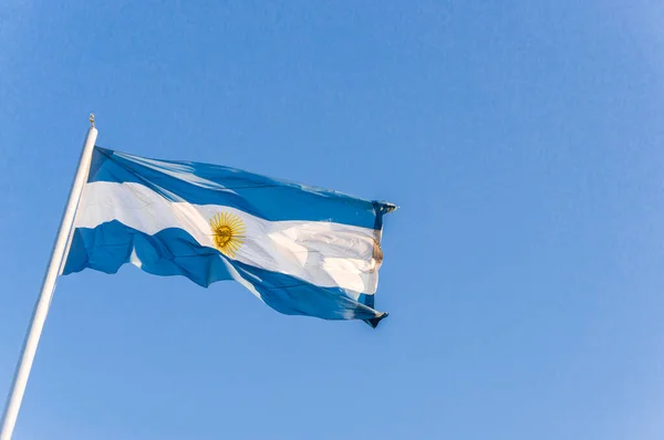 Arjantin bayrağı güneşli bir günde mavi gökyüzüne karşı el sallıyor. — Stok fotoğraf