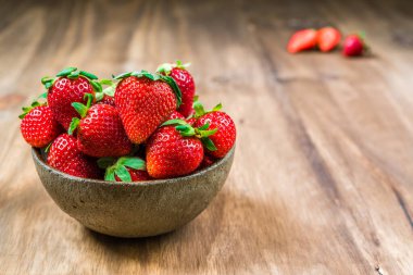 Ahşap arka planda taze renkli organik çilek kasesi. 