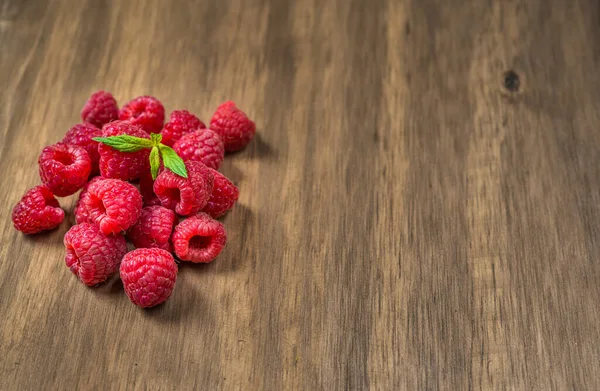 Verse kleurrijke biologische frambozen fruit tegen houten achtergrond. — Stockfoto