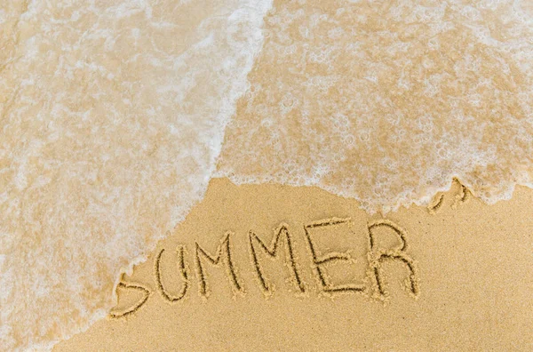 Zeegolven over de ondertiteling zomer geschreven op het zand. — Stockfoto
