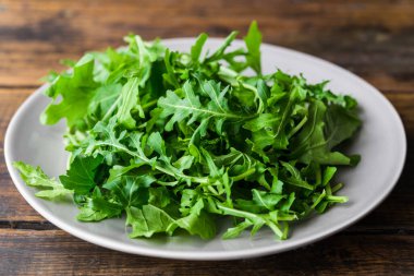 Arugula roket salatası ve ahşap arka plan.