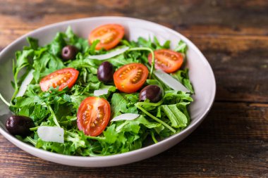 Roket salatalı salata kasesi, siyah zeytin ve vişneli domates.