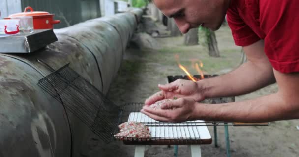 Чоловік готує м'ясо на вогні — стокове відео