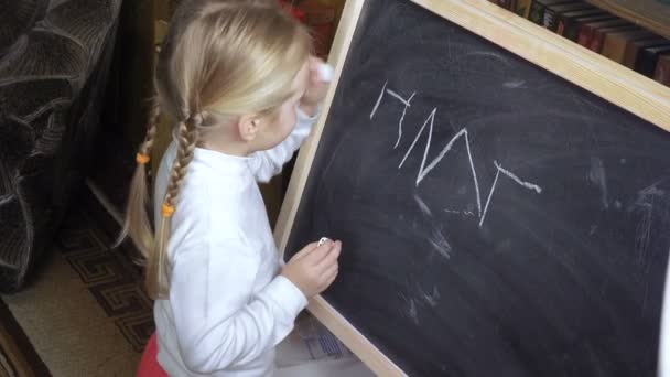 Mała dziewczynka rysuje kredę na tablicy — Wideo stockowe