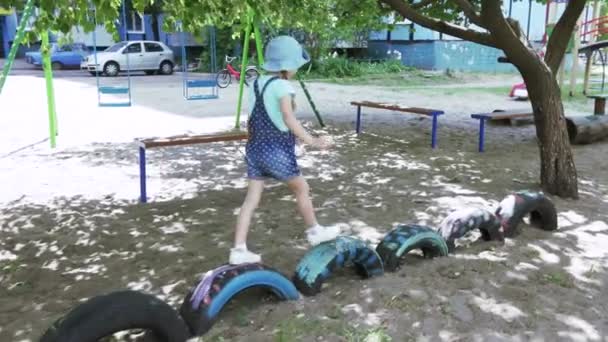 女児を実行しジャンプ遊び場で車のタイヤを埋める — ストック動画
