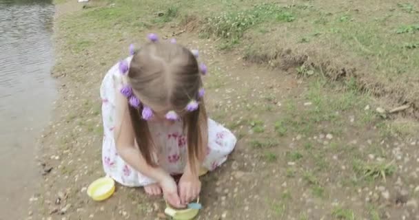 Girl child on the shore of a pond — Stock Video