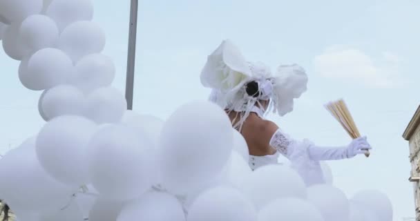 Танцоры на ходулях в костюмах белых эльфов или бабочек с надувными шарами — стоковое видео