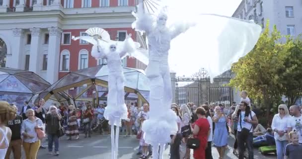 Bailarinas sobre zancos en trajes de elfos blancos o mariposas con bolas inflables — Vídeos de Stock