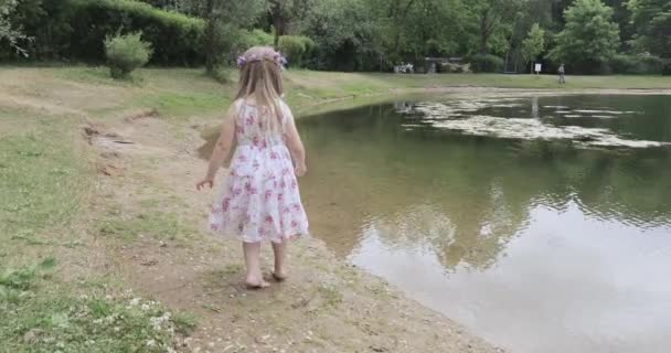 Girl child on the shore of a pond — Stock Video