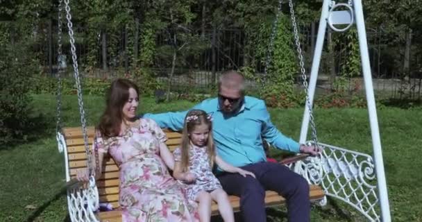 Meisje kind op een schommel met haar ouders — Stockvideo