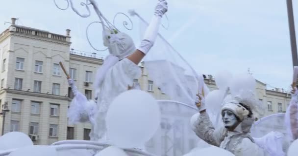 Танцоры на ходулях в костюмах белых эльфов или бабочек с надувными шарами — стоковое видео