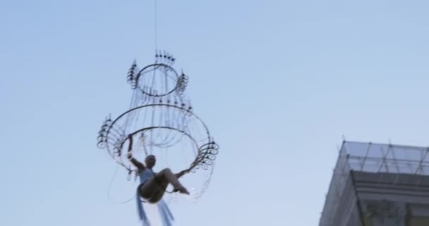 Menina acrobata em vestido branco no ar acima da rua em um grande lustre na corda — Vídeo de Stock