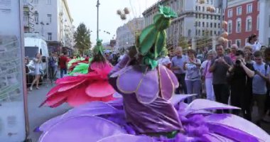 Renkli büyük çiçek takım elbiseli stilts dansçılar