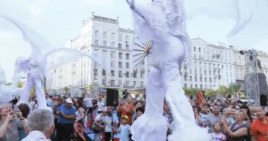 Beyaz elfler veya kelebekler Ulusal teketim ürünleri ile takım elbiseli stilts dansçılar