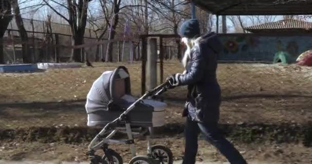 Junge Mutter geht mit Kinderwagen — Stockvideo