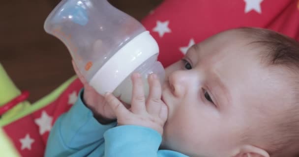 Niño aprende a beber de un biberón — Vídeo de stock