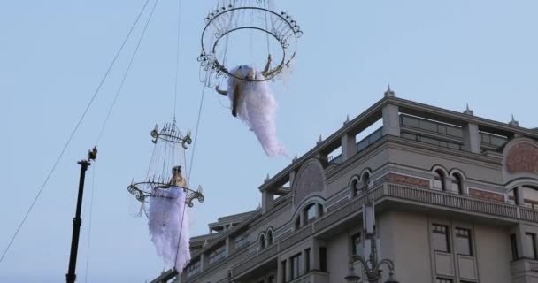 Chica acróbata en vestido blanco en el aire por encima de la calle en una gran lámpara de araña en la cuerda — Vídeo de stock