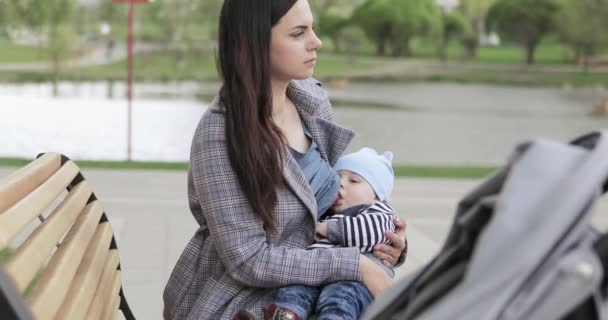 Мама кормит грудью ребенка в парке — стоковое видео