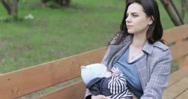 Anne parkta bir çocuğu emzirir.