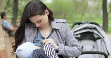 Anne parkta bir çocuğu emzirir.