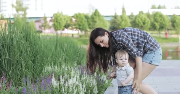 Mamma med ett barn nära en blomma säng — Stockvideo