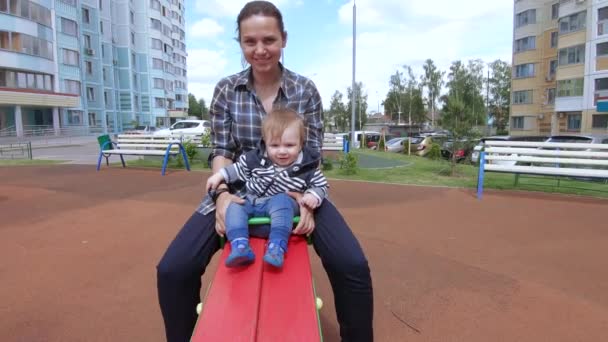 Moeder en zoon rijden op een schommel — Stockvideo