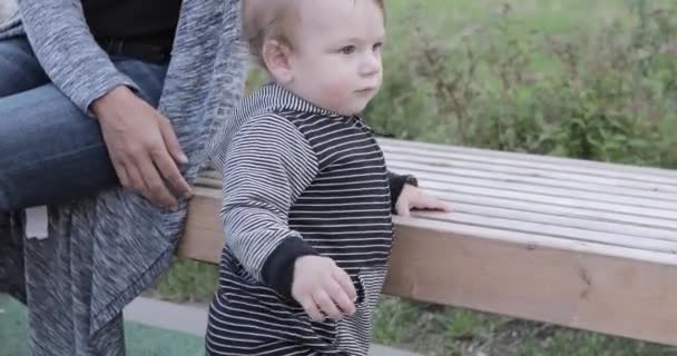 Μωρό αγόρι κοντά στο ξύλινο παγκάκι — Αρχείο Βίντεο