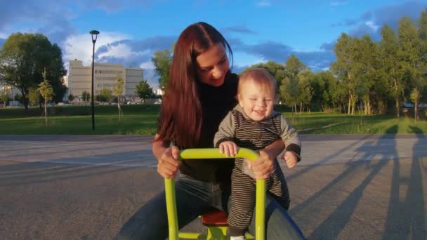 Mamma con un bambino sull'altalena di ferro — Video Stock