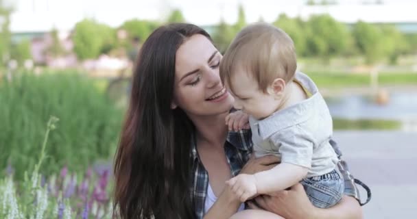 Mamá con un niño cerca de un macizo de flores — Vídeos de Stock