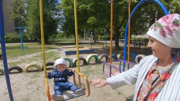 Бабуся з онуком на гойдалці — стокове відео