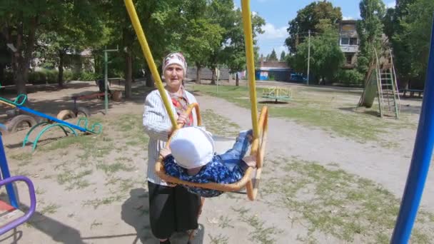 Grand-mère avec un petit-fils sur une balançoire — Video