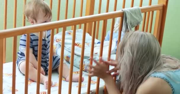 Ребенок развлекается в кроватке — стоковое видео