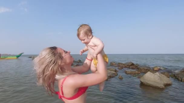 Девушка целует мальчика в море — стоковое видео