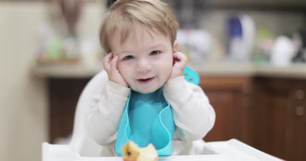 Niño se sienta y sostiene las orejas — Vídeo de stock