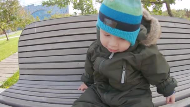 Menino infantil em um banco de madeira — Vídeo de Stock