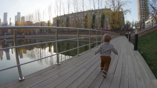 Child boy runs on a wooden platform — ストック動画