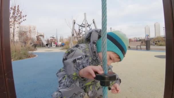 Мальчик в комбинезоне на детской площадке — стоковое видео