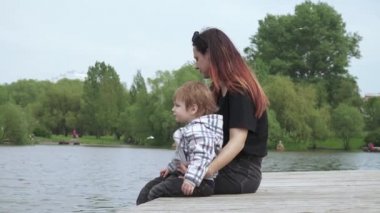 Oğlan ve anne tahta iskelede oturuyor.