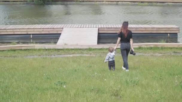 Junge mit mutter gehen auf einem hölzernen pier — Stockvideo