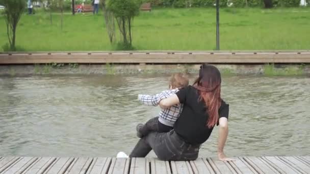 Niño con mamá sentarse en un muelle de madera — Vídeo de stock
