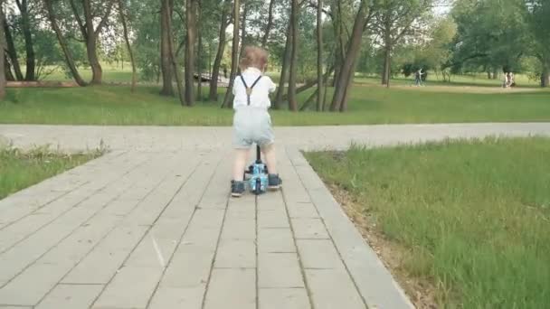 Rapaz aprende a andar de scooter — Vídeo de Stock