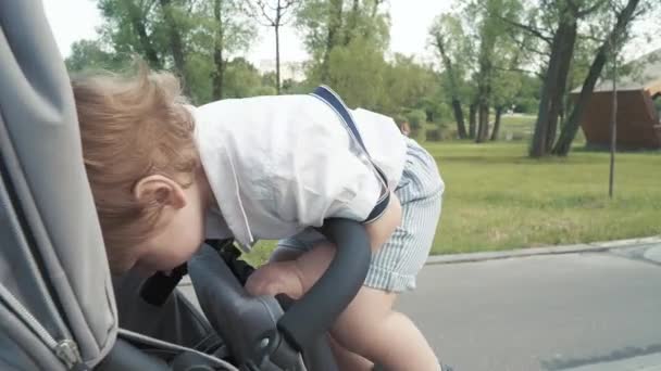 Мальчик забирается на коляску — стоковое видео