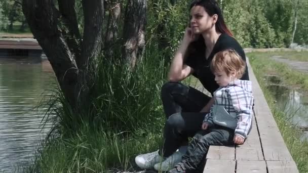 Garçon avec maman assis sur une jetée en bois — Video